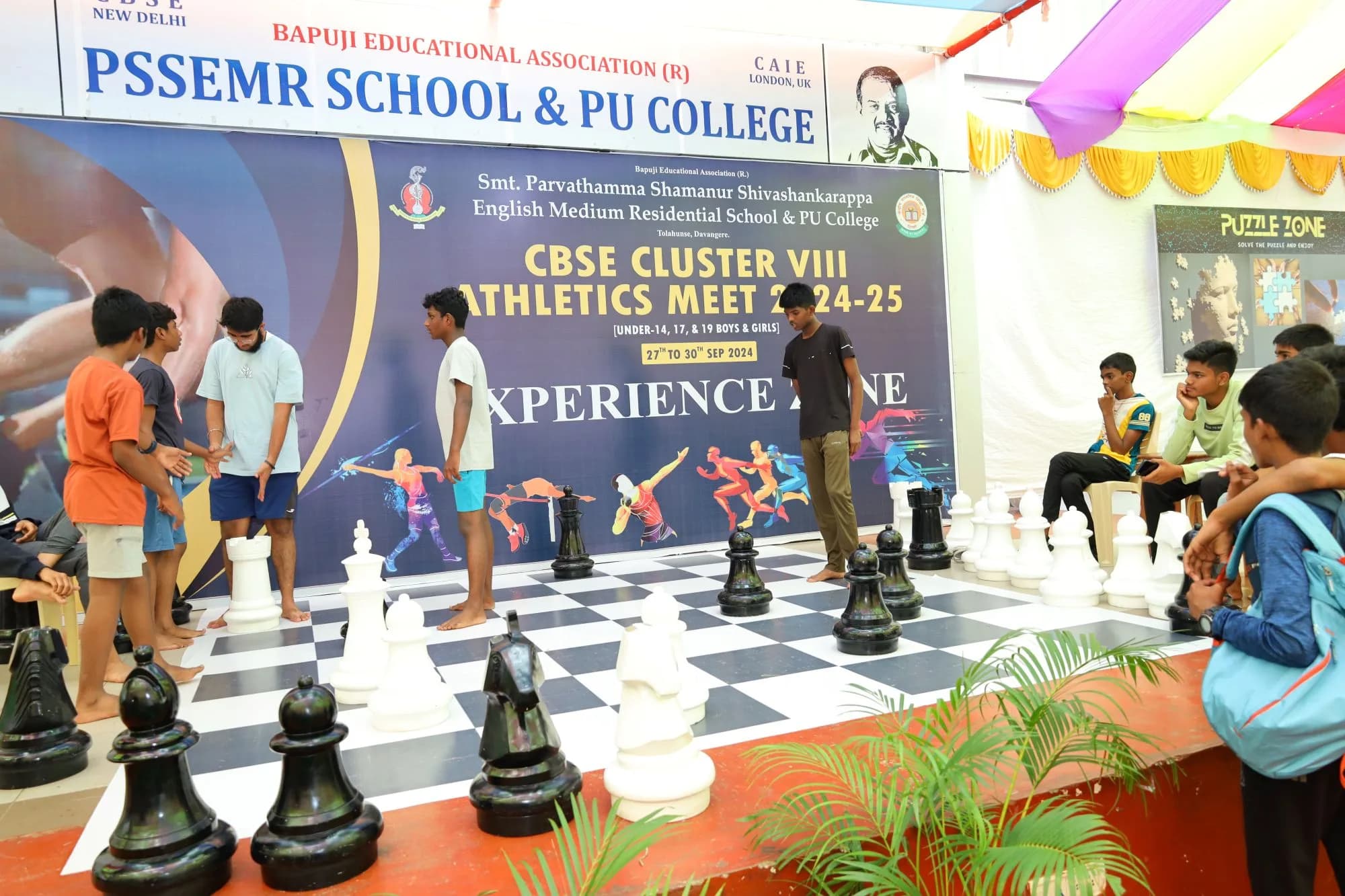 The Experience Zone beside the arena, with a lawn-sized chess board in play — CBSE Cluster VIII Athletics Meet, 2024.