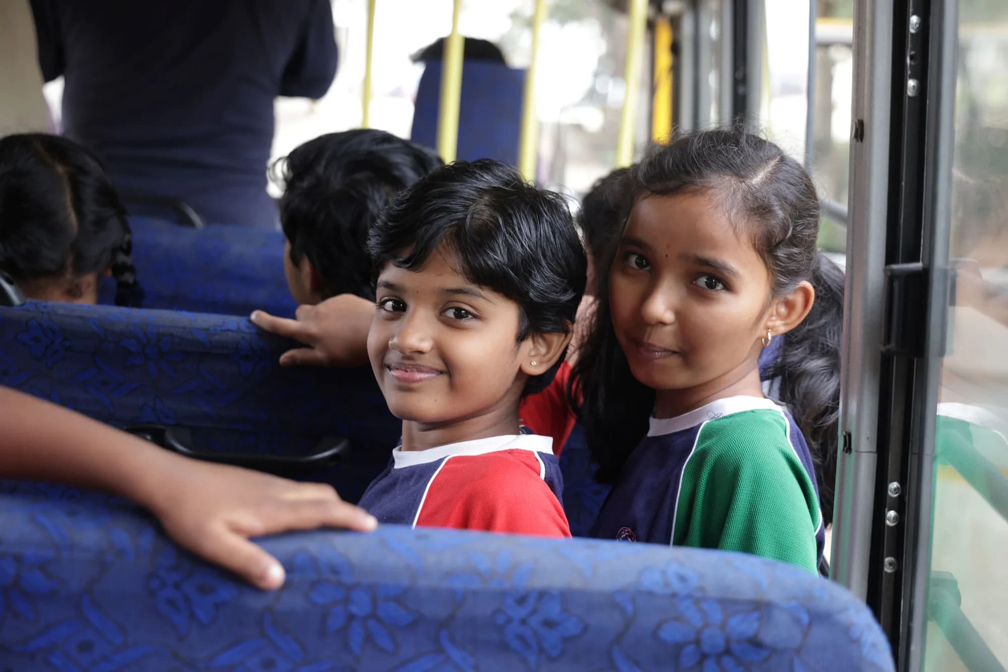 Two children smiling in their seats on a PSSEMR School bus