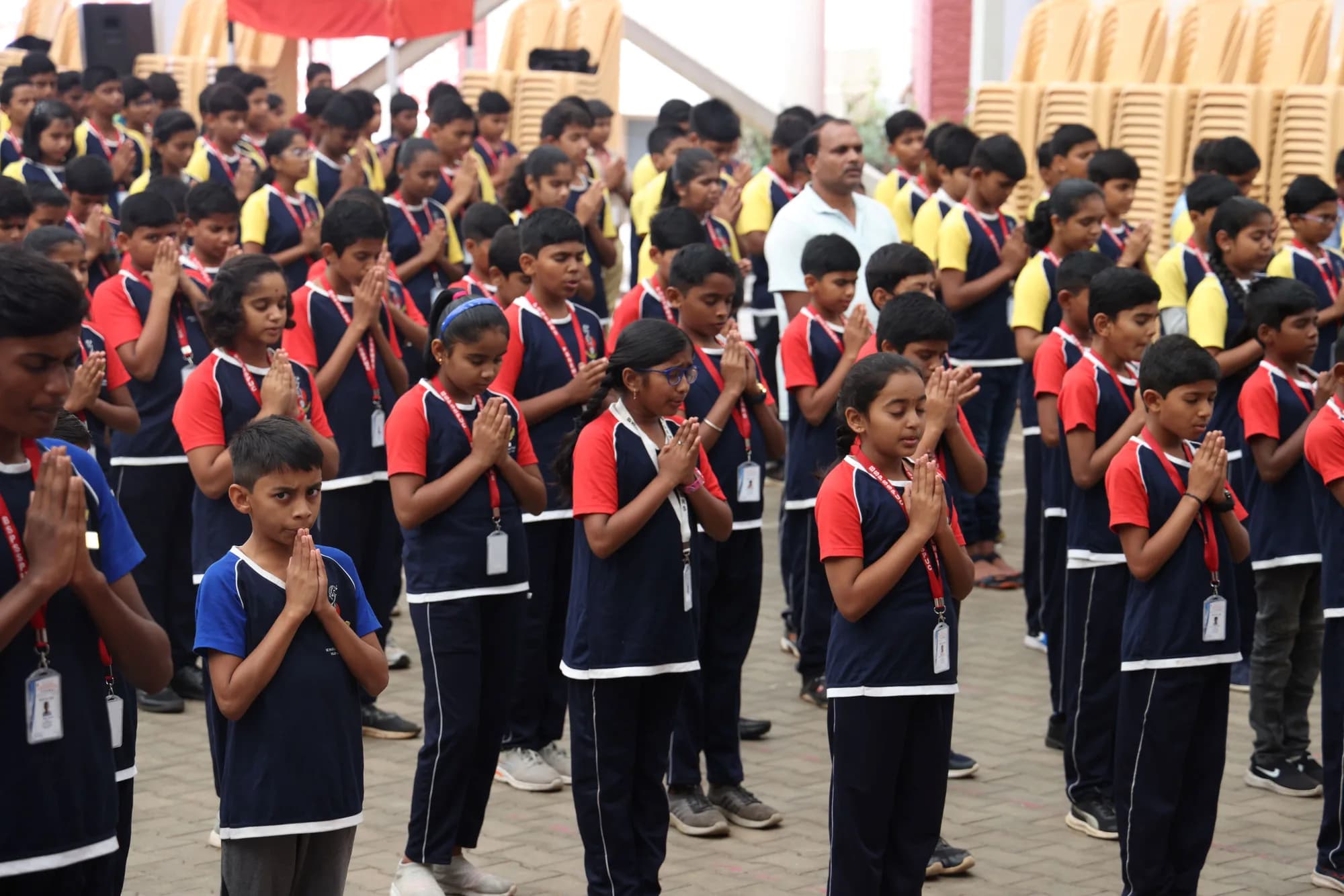 Rows of students at morning assembly at PSSEMR School, palms joined in prayer
