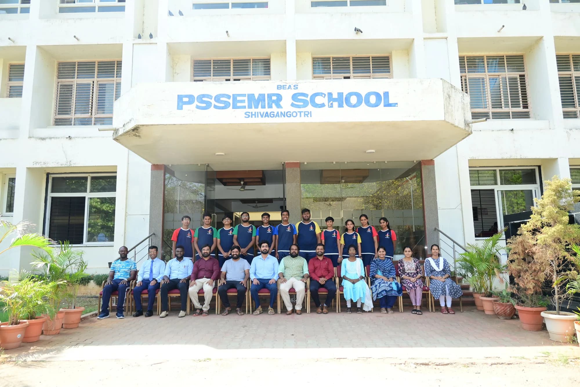 Staff and senior students seated beneath the PSSEMR School name above the entrance