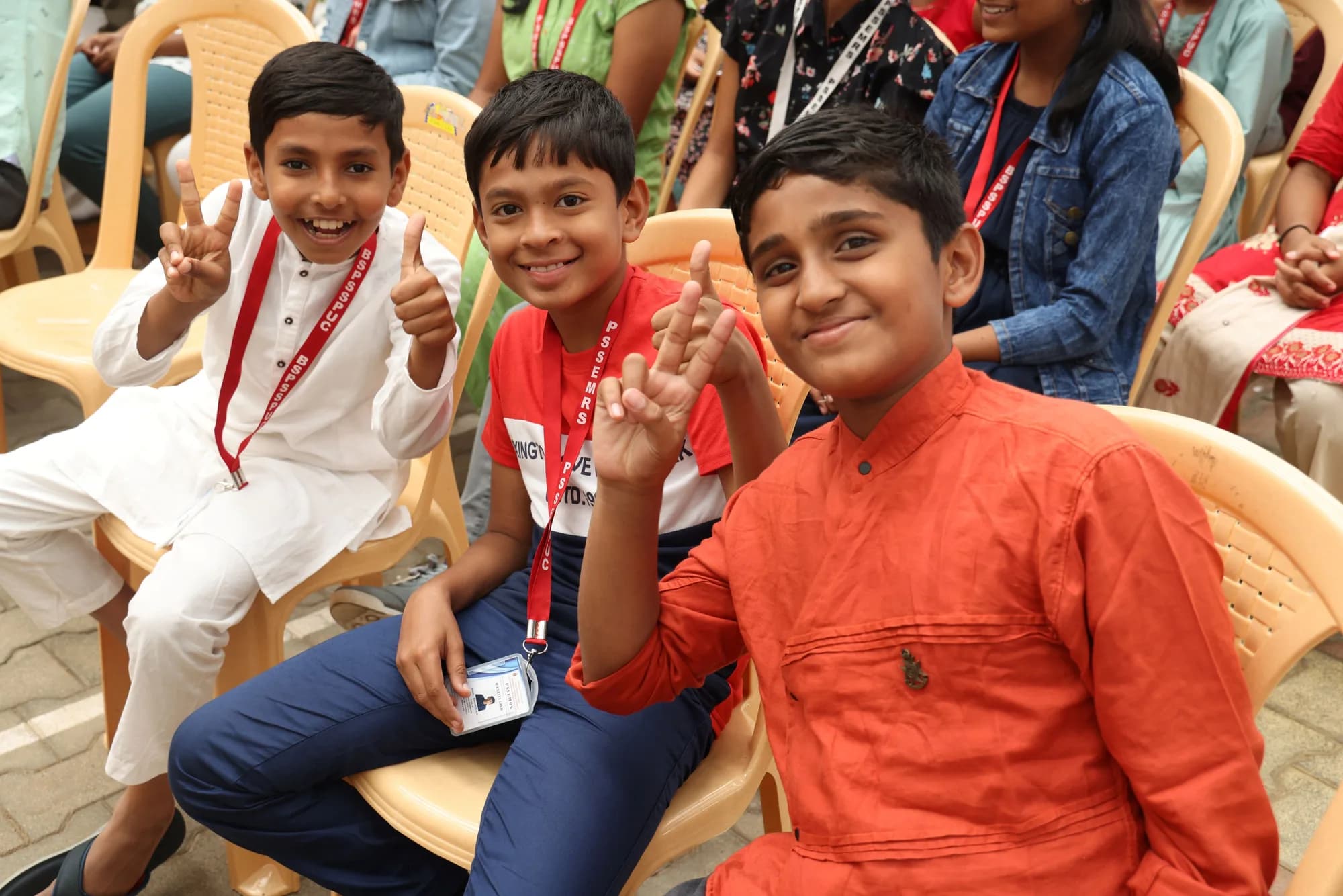 Three boys in festive dress with PSSEMR School lanyards, grinning to camera