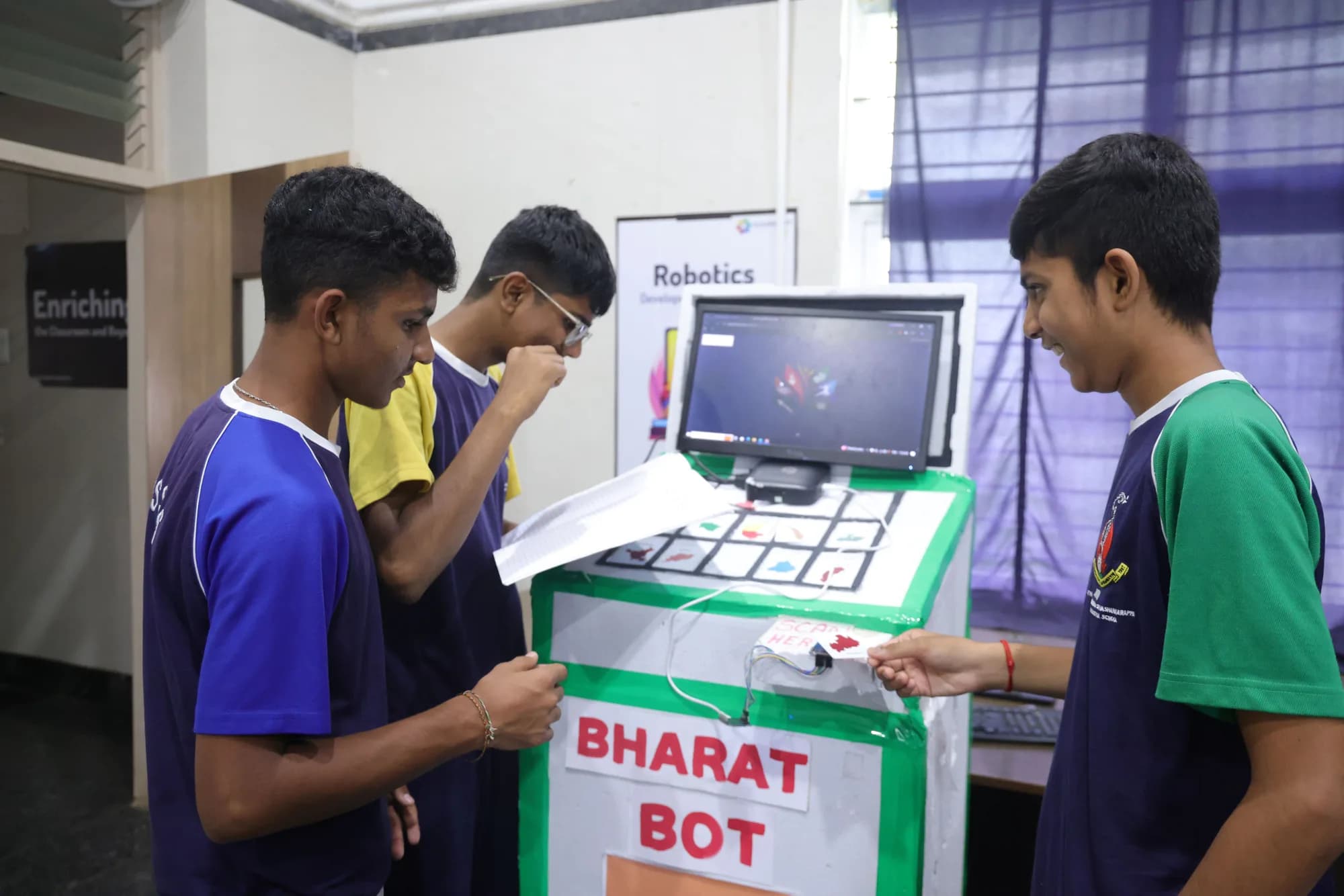 Students at a home-made kiosk labelled BHARAT BOT, with a monitor and a picture keypad