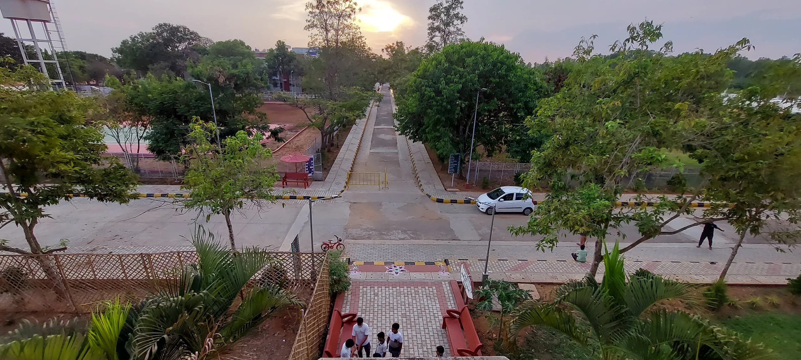 The PSSEMR School campus at dusk in Davangere, its tree-lined internal road running east