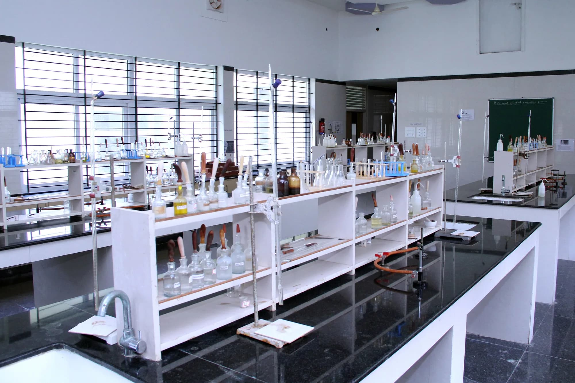 Racks of labelled reagent bottles in the PSSEMR School chemistry laboratory