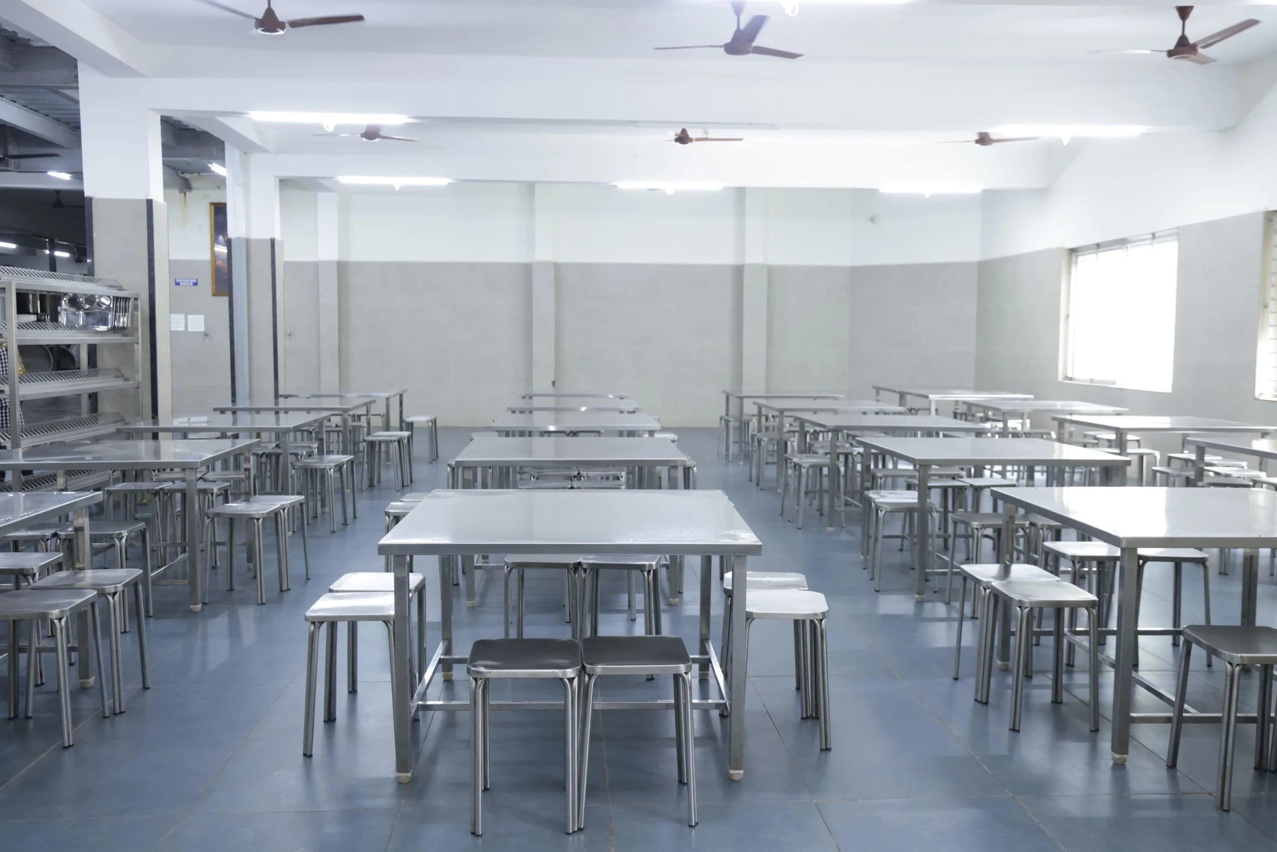 The PSSEMR School dining hall, lined with stainless steel tables and stools