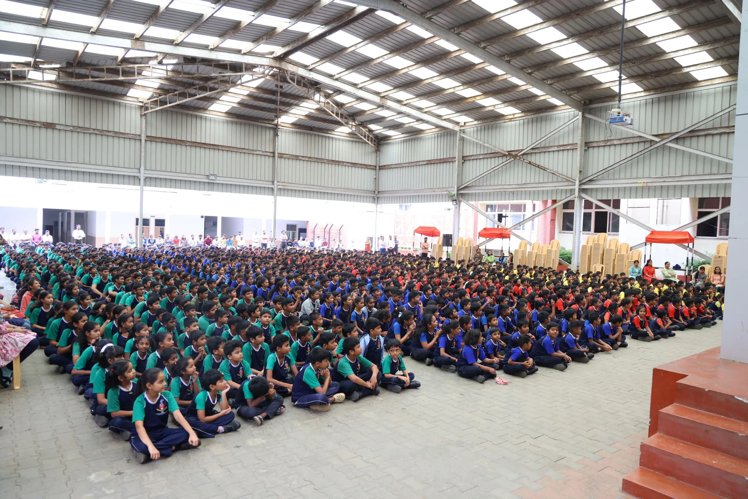 The whole of PSSEMR School seated in house colours under the assembly shed