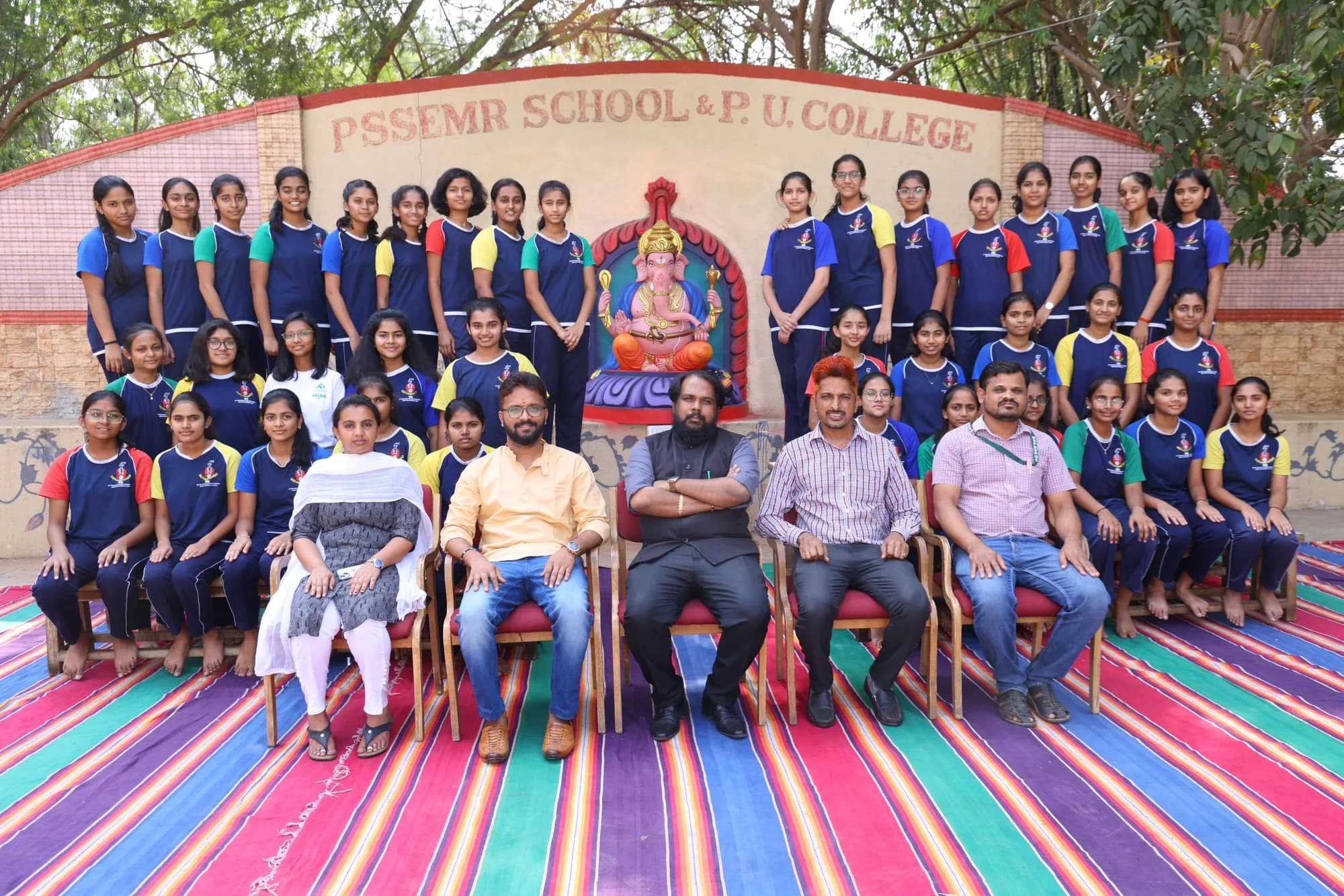 Rows of girls in house sports kit with staff, before the PSSEMR School name