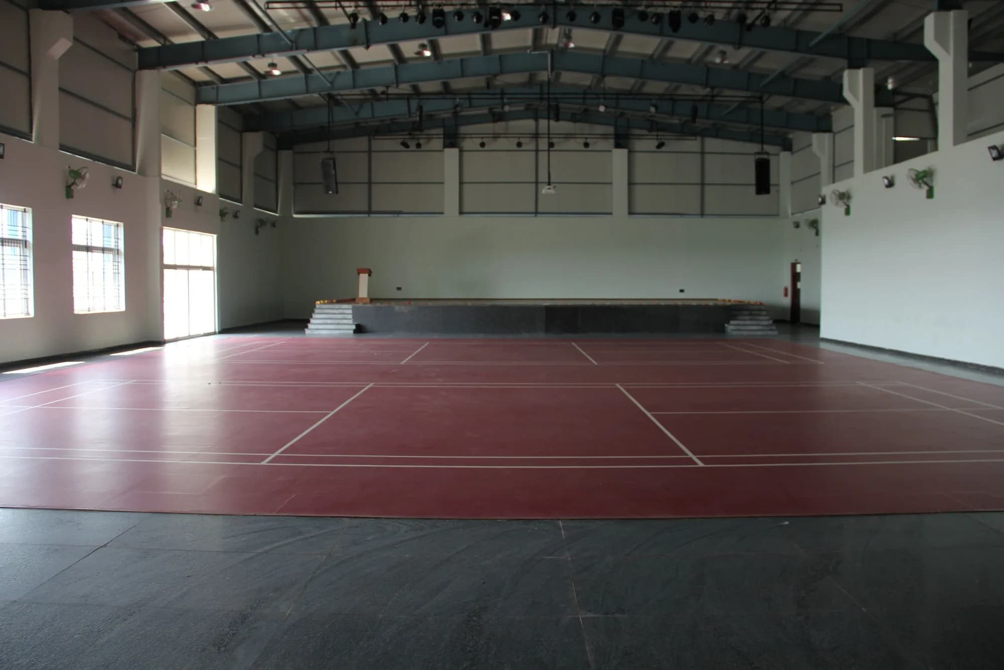 The indoor hall at PSSEMR School, with a marked court and a raised granite stage