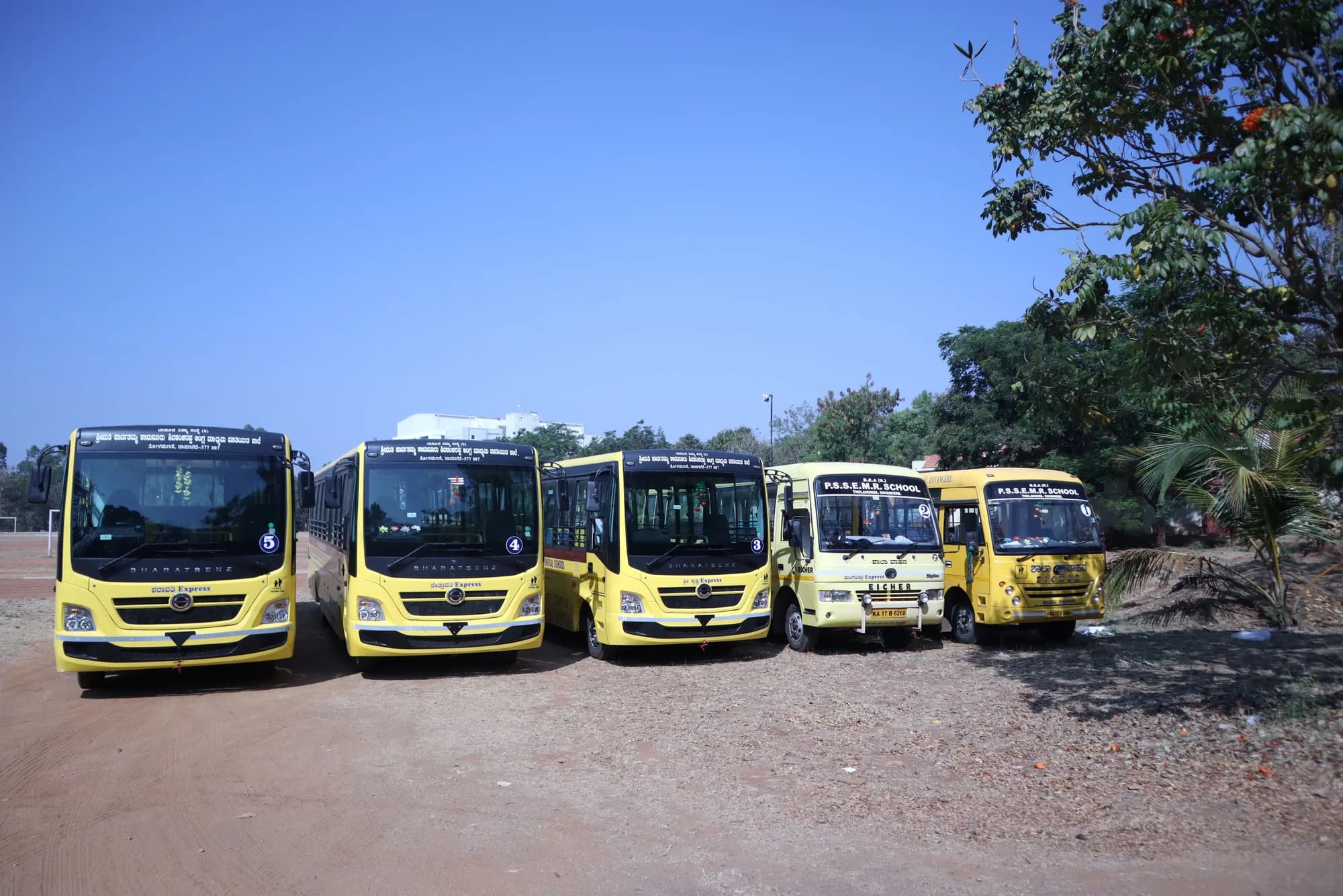 Five PSSEMR School buses lined up, the school name painted on the smaller two