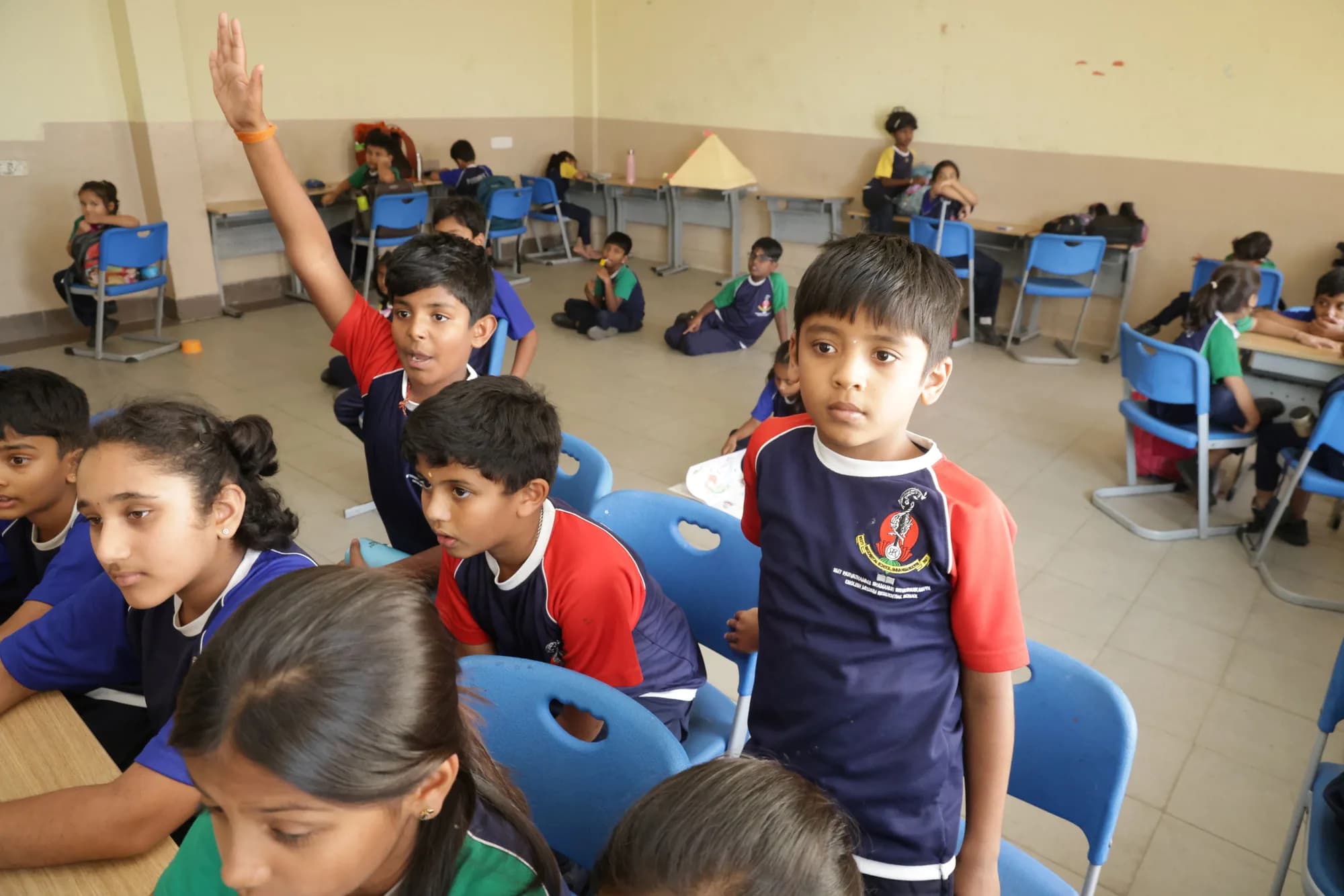 A boy raising his hand to answer in class at PSSEMR School