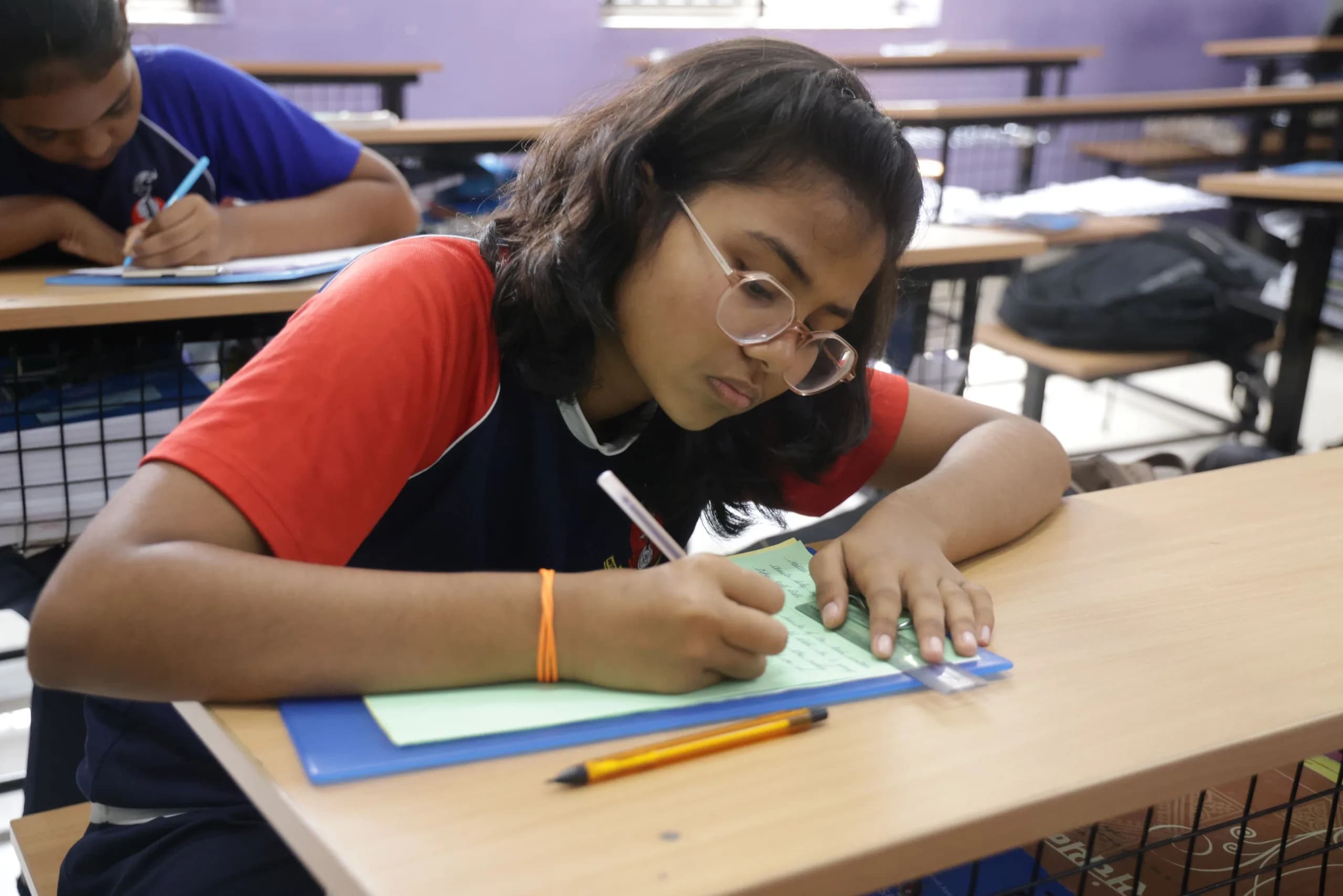 A student writing carefully during a written round at PSSEMR School